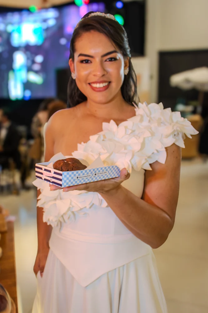 Convidada de um evento segurando uma caixa Be Cookie com cookie
