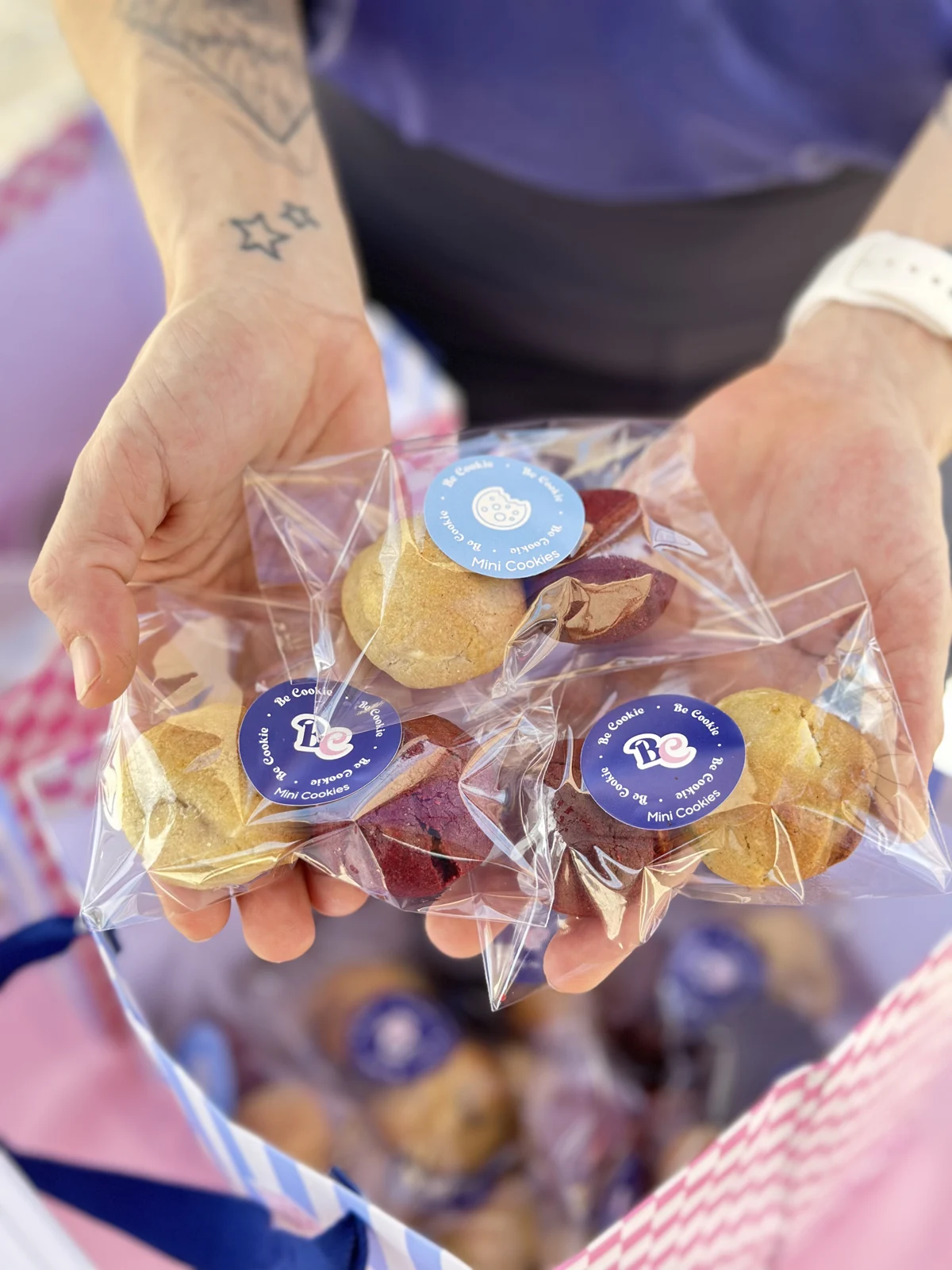Mini cookies embalados individualmente com adesivos Be Cookie, apresentados nas mãos